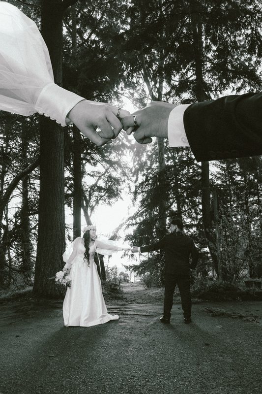 Black and white, two hands reaching with the couple far below