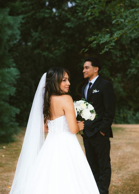 Bride looking back over her shoulder, groom beside her with the bouquet