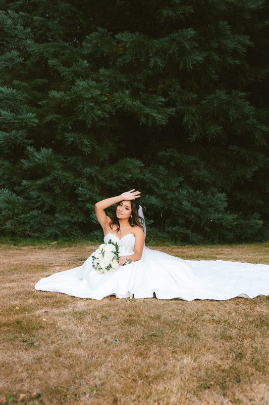 Bride seated on the grass, dress spread around her