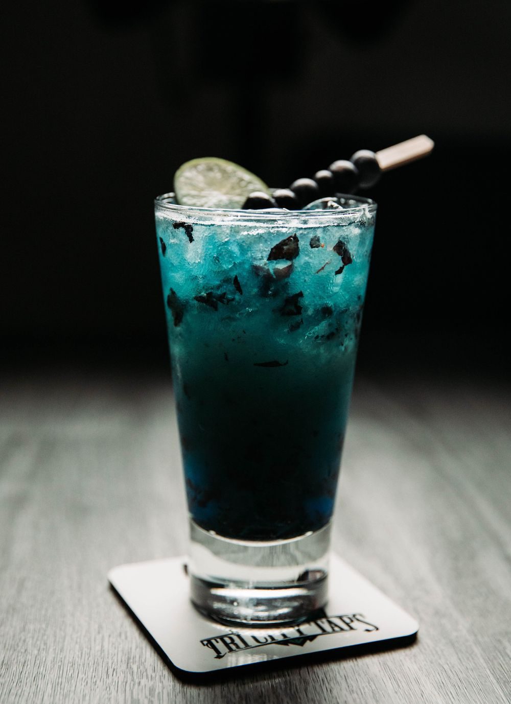Blue cocktail on a dark bar