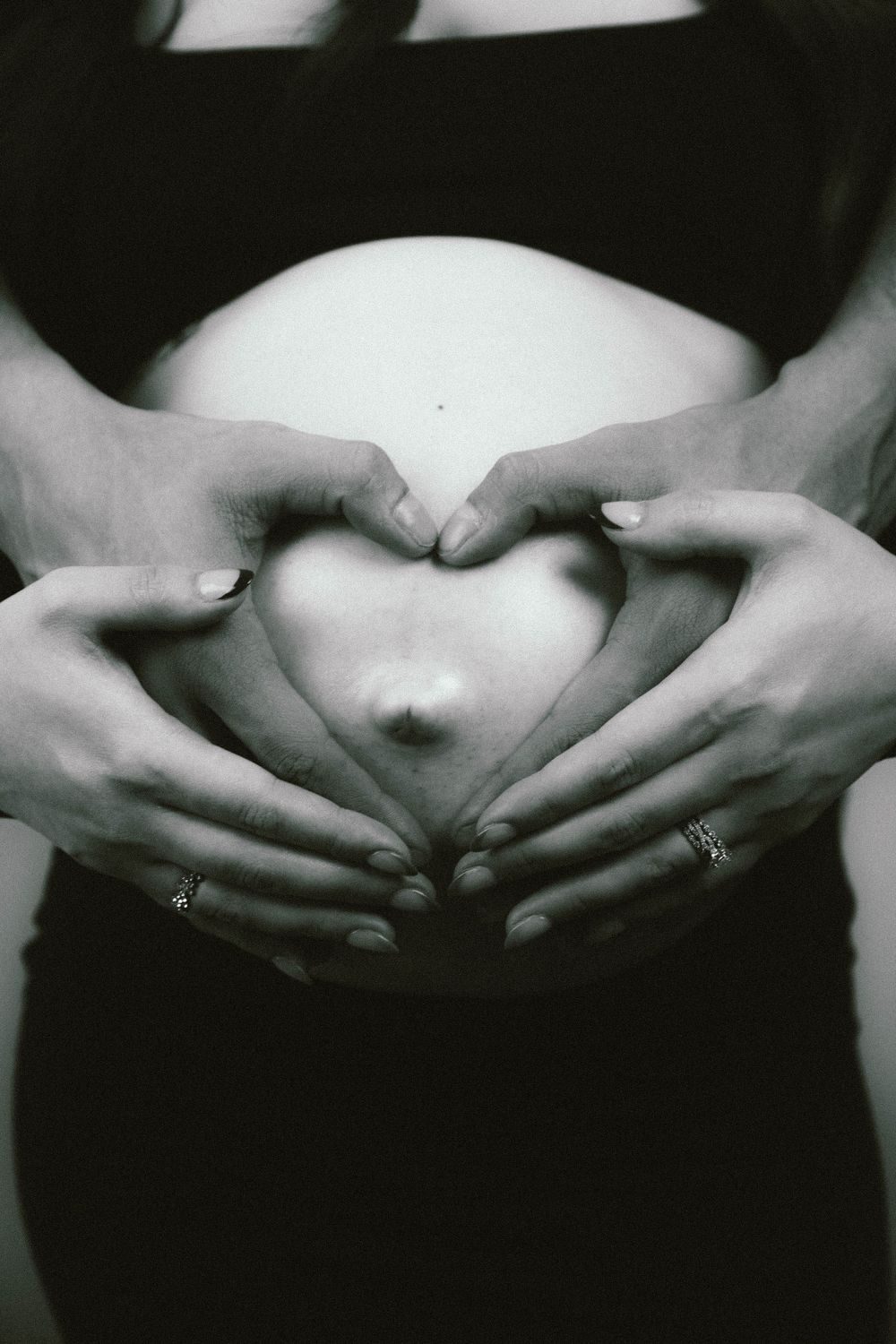 Black and white hands making a heart on a belly