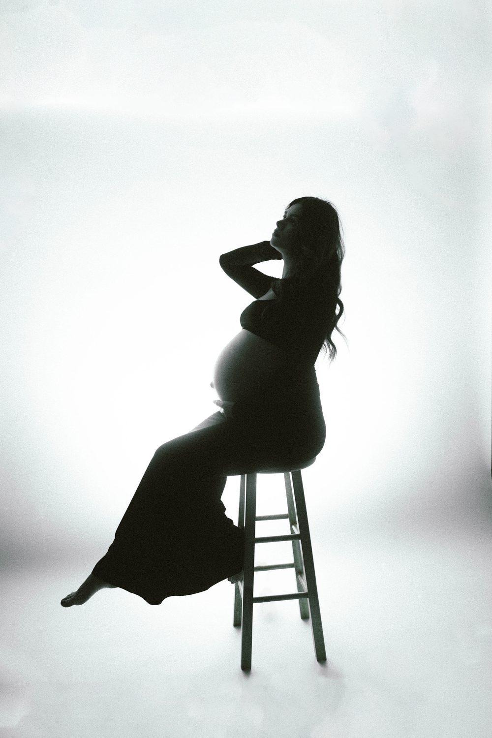 Maternity silhouette on a stool against white