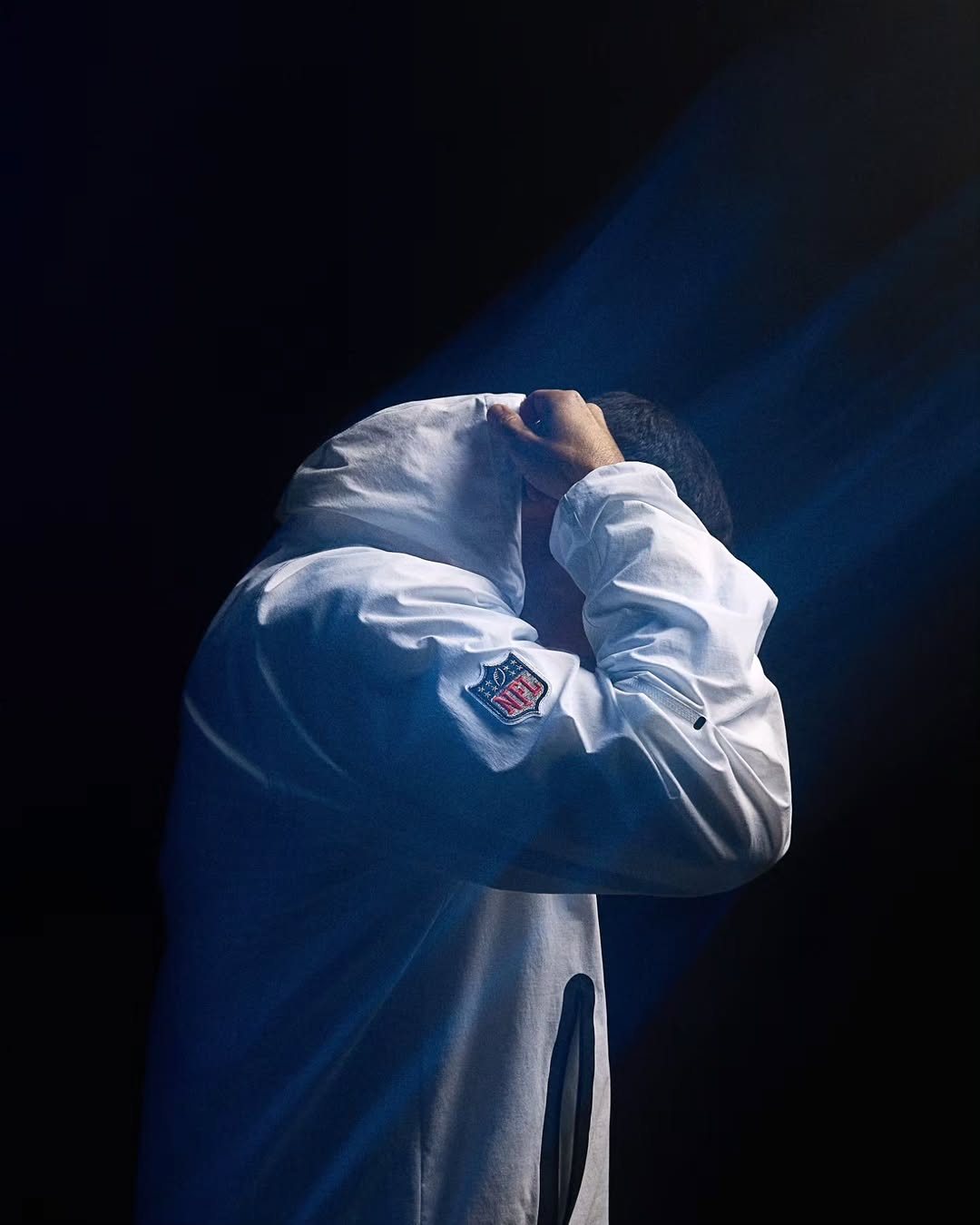 Model pulling up a white hoodie in blue light