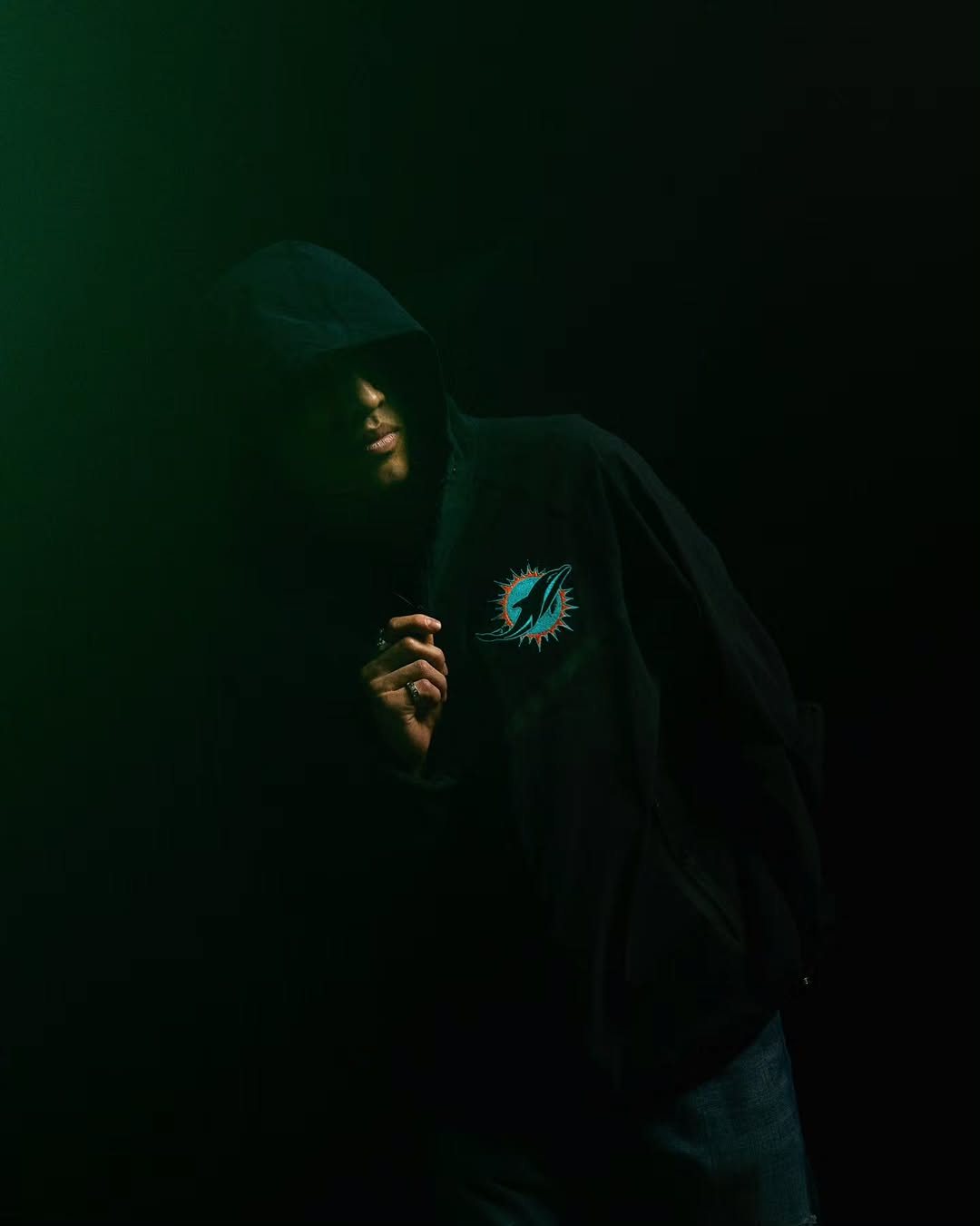 Man in a black Dolphins hoodie in green light