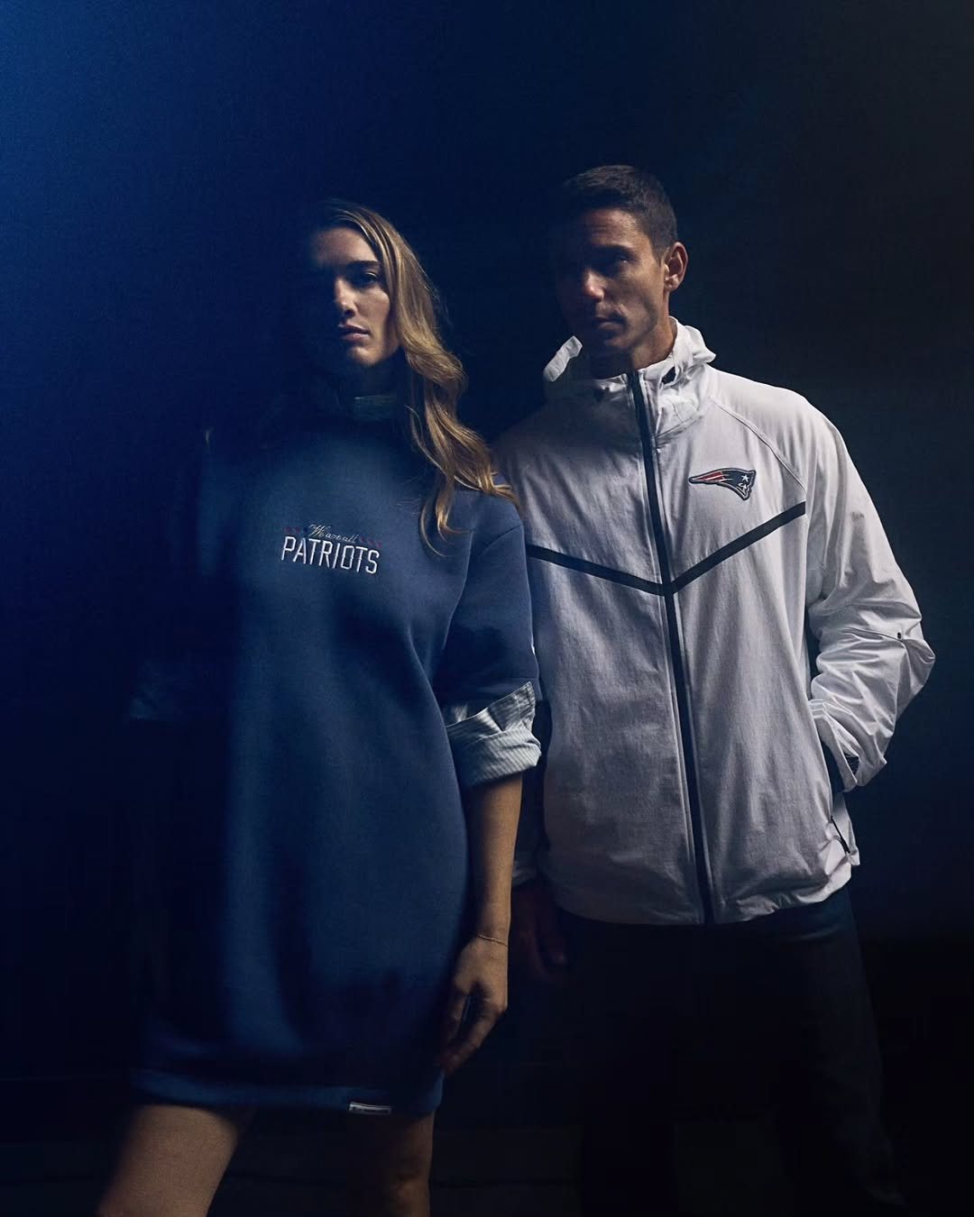 Two models in Patriots gear in blue light