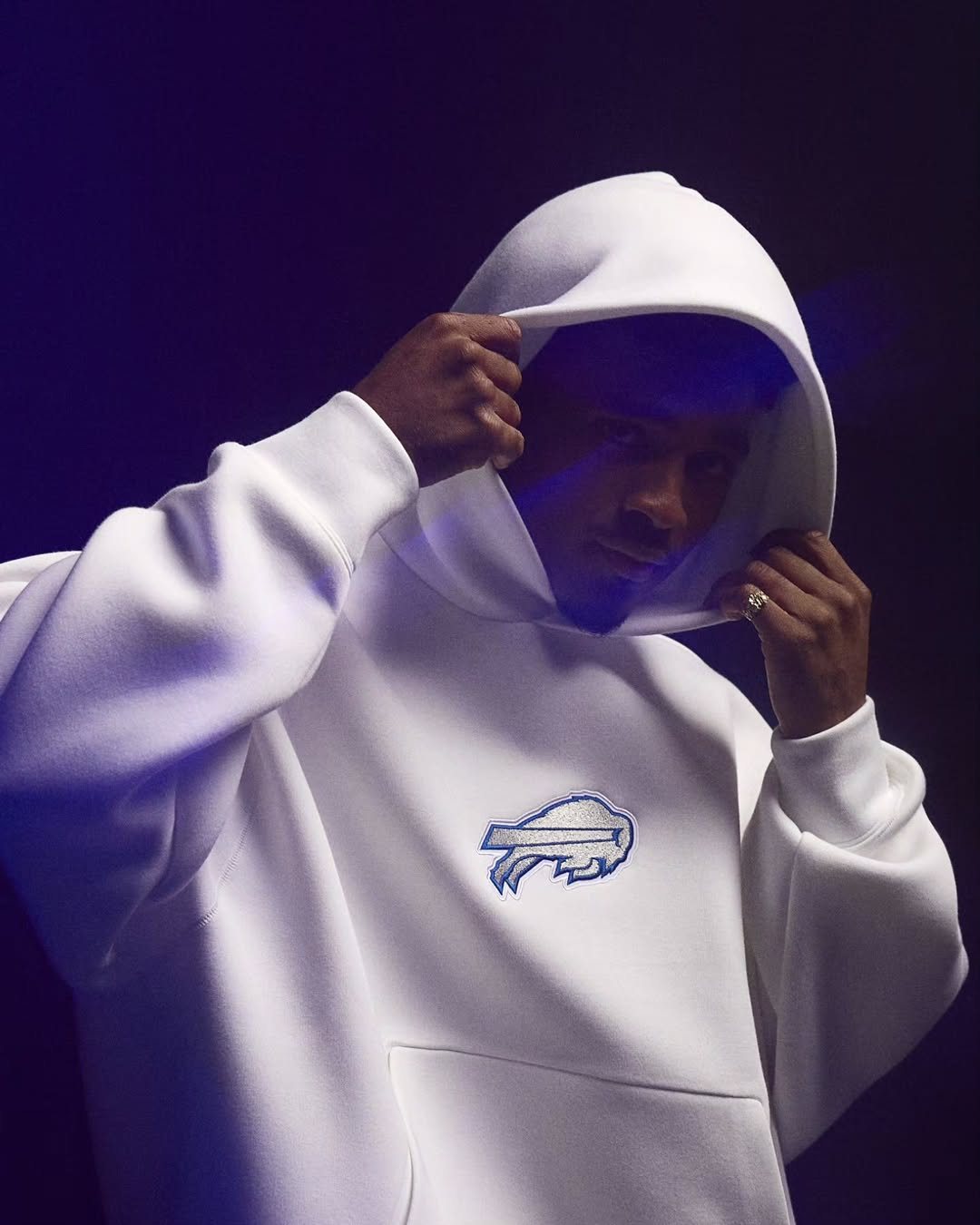 Man in a white Bills hoodie lit in violet