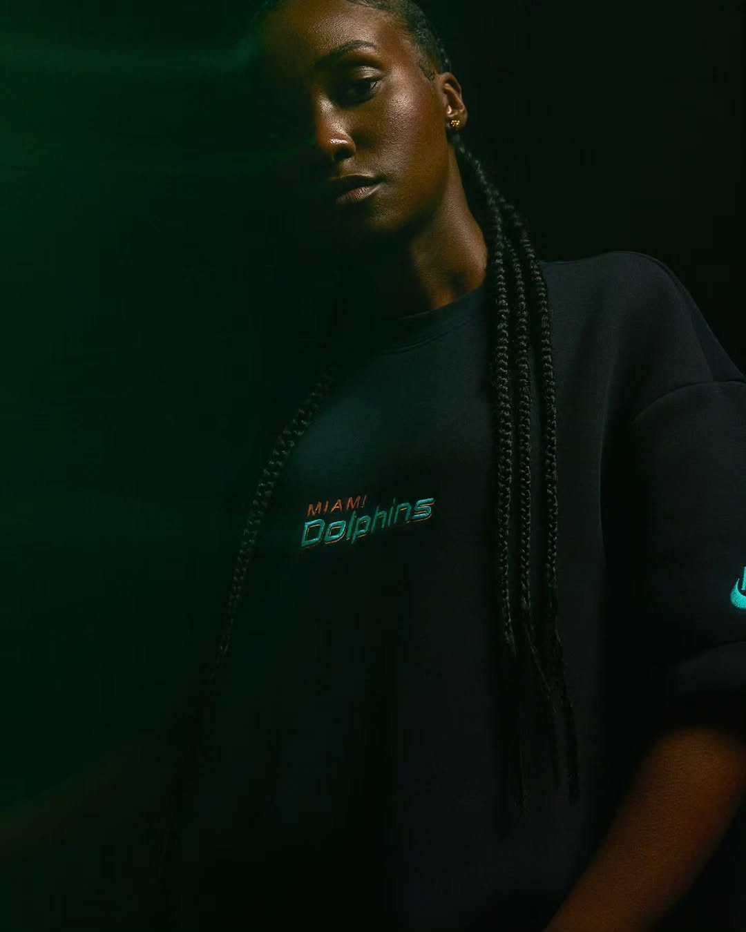 Woman in a black Dolphins tee in green light