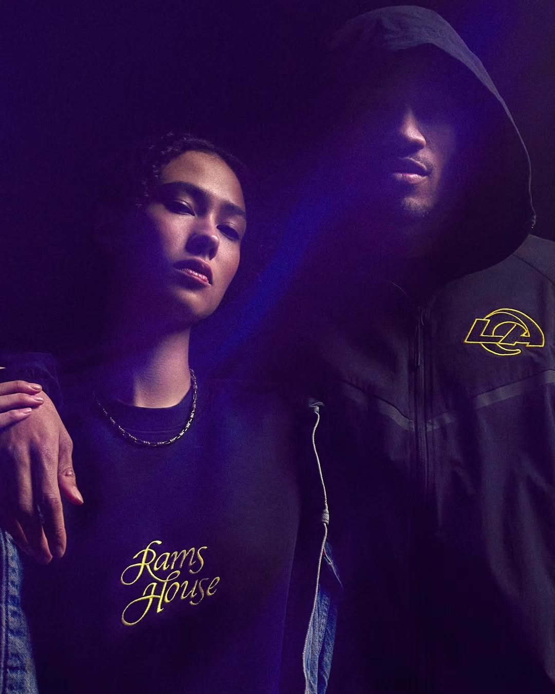 Two models in Rams gear in violet light