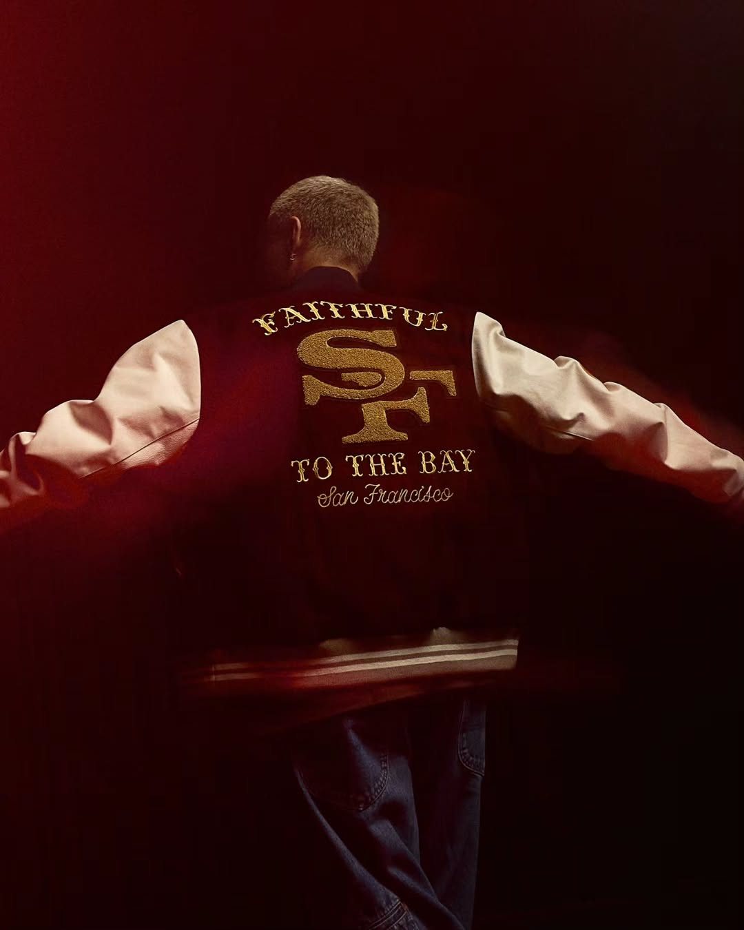 Man in a 49ers varsity jacket with red light trails