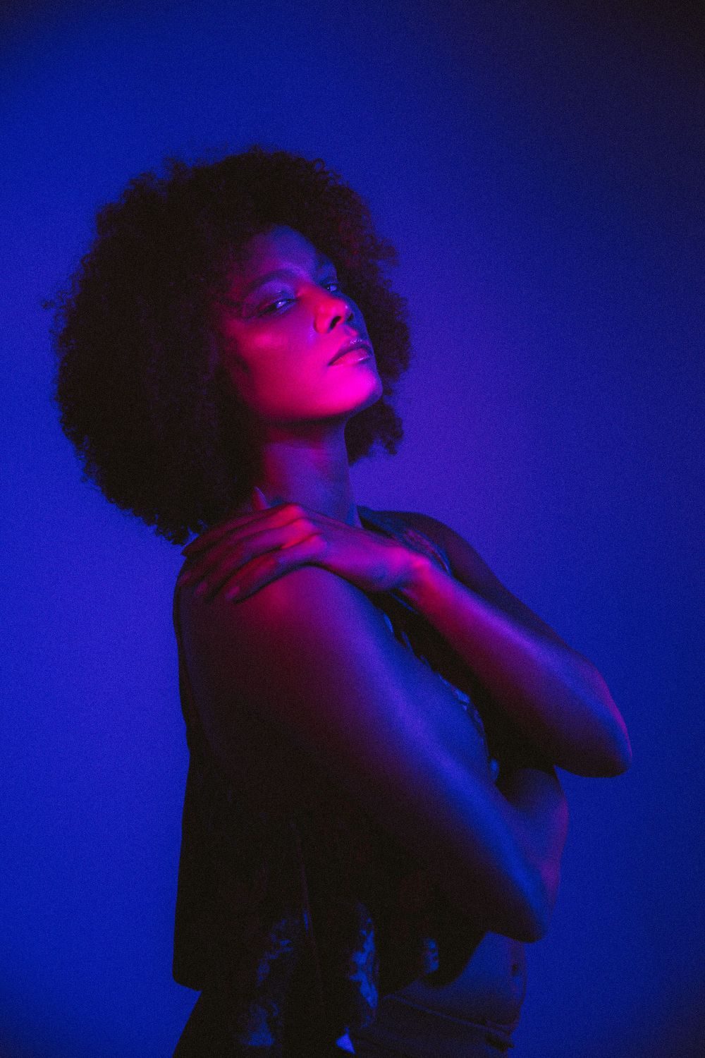 Woman with curly hair lit in blue and magenta