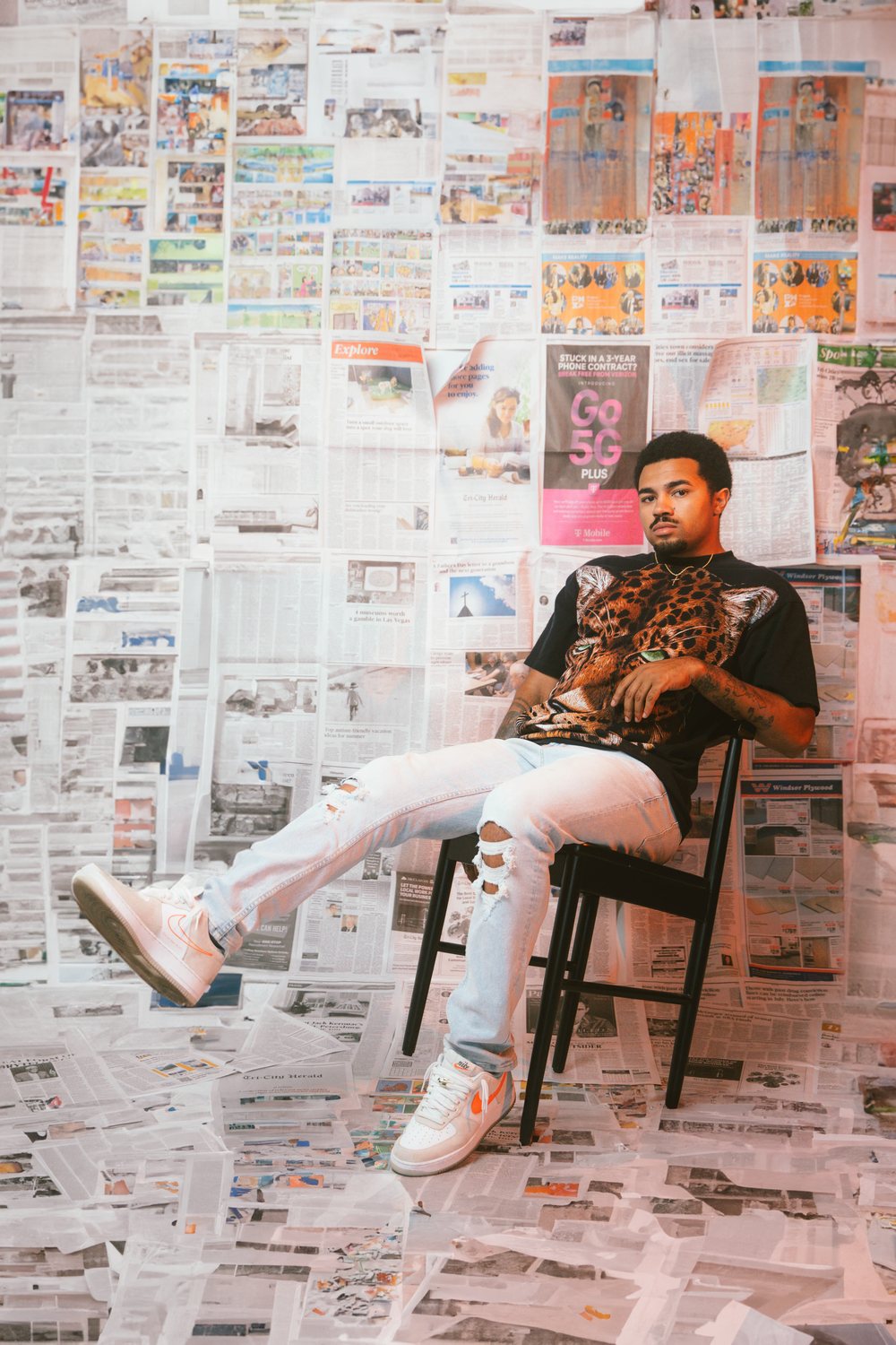 Man seated in a room papered with newspaper