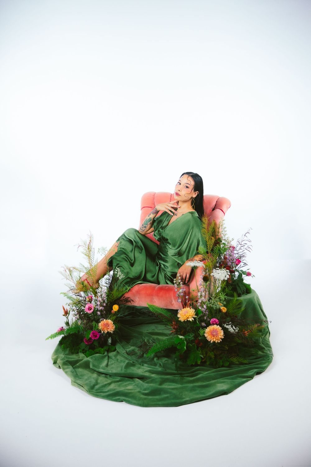 Woman in a green dress on a chair surrounded by flowers