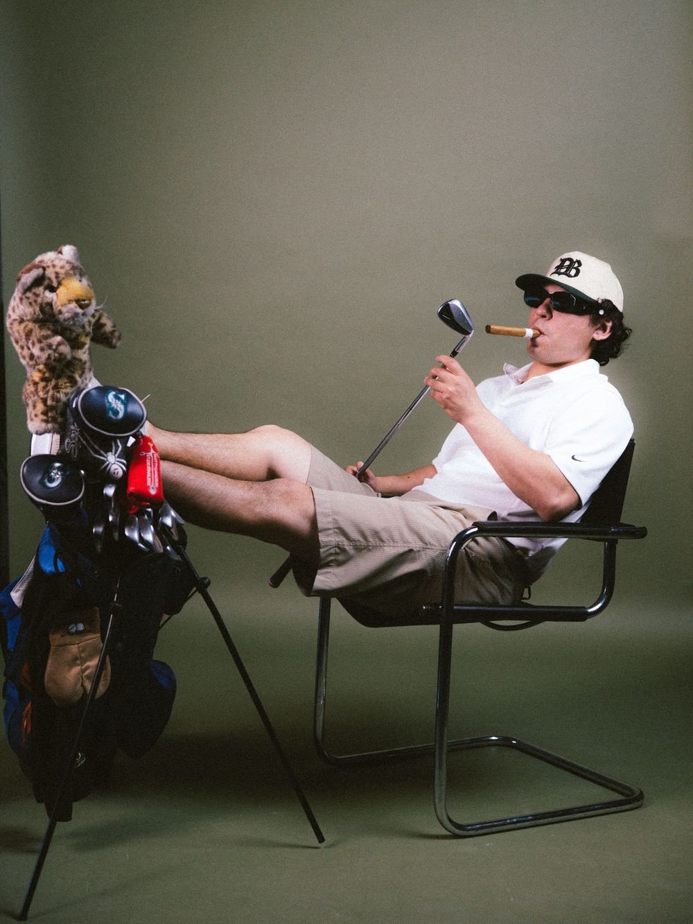 Man in a bucket hat reclining with a golf bag
